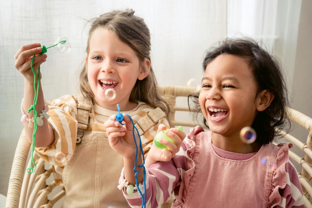 Two happy girls are enjoying their time blowing bubbles, capturing joyful childhood moments.
